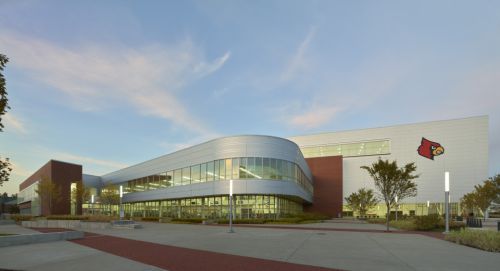 Student Recreation Center and a lightly cloudy sky; sidewalks and light poles surround the building