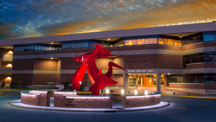 College of Business with a lit up structure in front of Harry Frazier Hall; sun is setting
